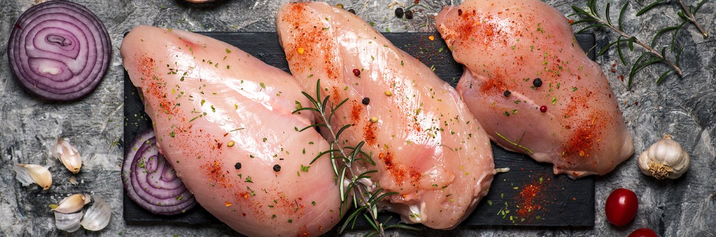 Rohes Geflügelfleisch gewürzt auf einem Brett.