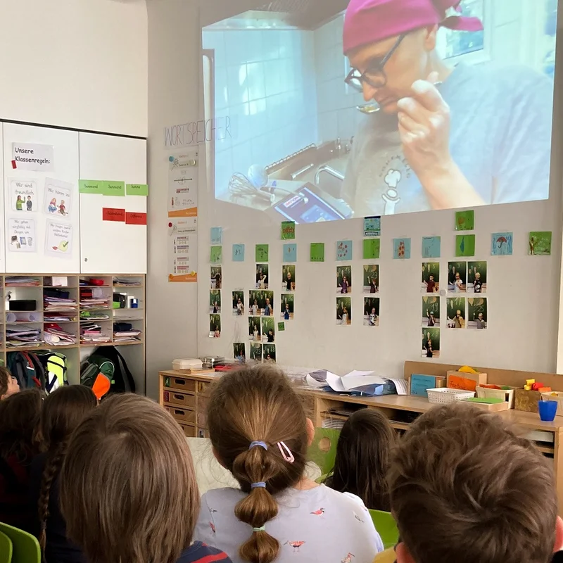 Grundschulkinder schauen einen Film zu ihrem Catering-Unternehmen an. Klick führt zu Großansicht im neuen Fenster.