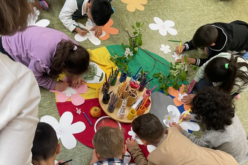 Kinder sitzen im Kreis auf dem Boden und arbeiten mit dem Material "Bauernhof im Koffer".