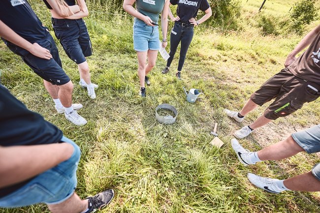 Menschen, die in einem Kreis um ein zu beprobendes Bodenstück stehen.