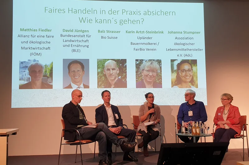 Fünf Menschen sitzen nebeneinander auf einem Podium. Klick führt zu Großansicht in neuem Fenster, schließen per ESC.