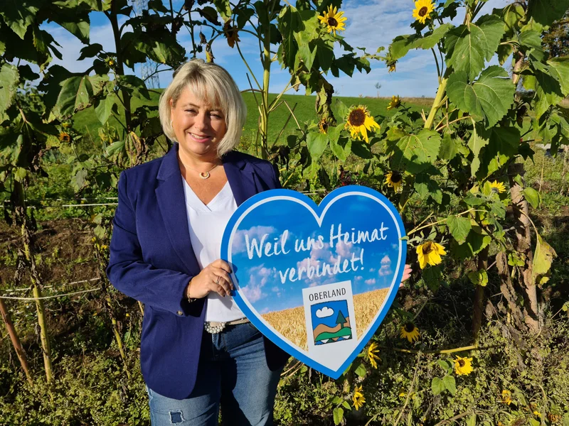 Adriane Schua vor Sonnenblumen mit einem blauen Herz in der Hand