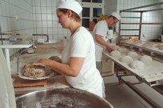 Bäckerinnen und Bäcker in einer Backstube bei der Zubereitung von Teig. Klick führt zu Großansicht.
