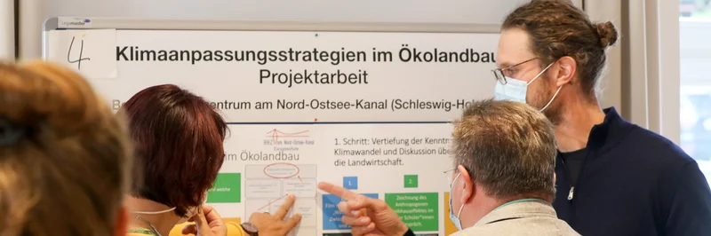 Menschen stehen vor einer Plakatwand.