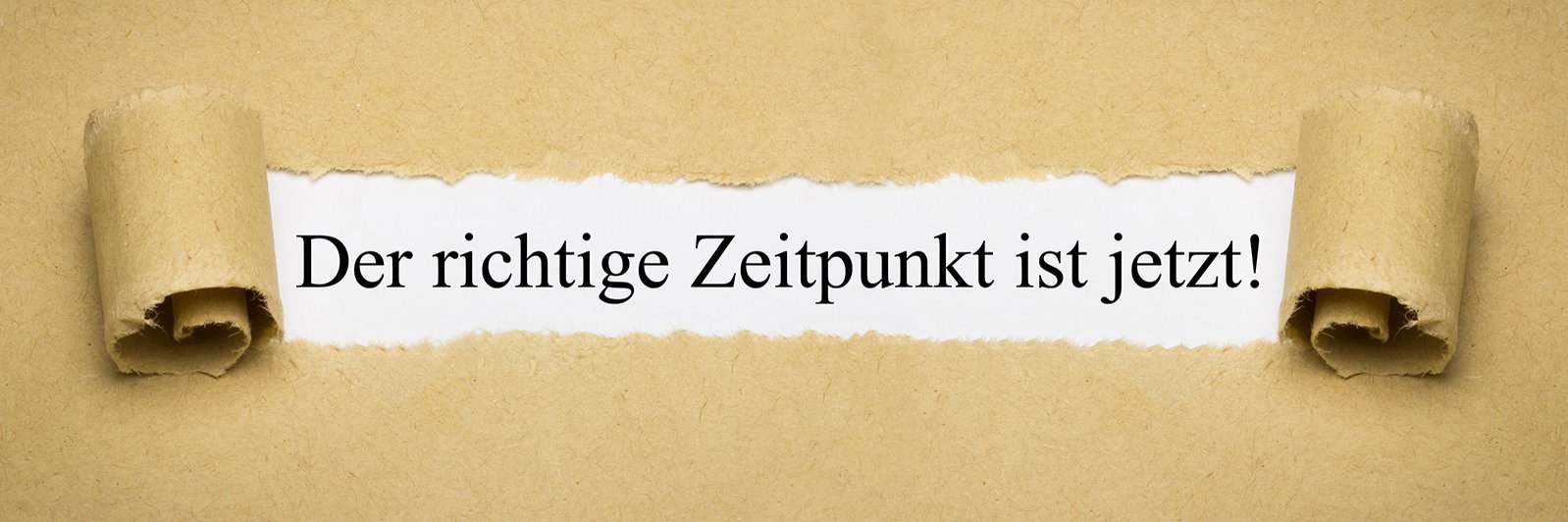 Ein sandfarbener Untergrund auf dem eine weiße Fläche freigeschaufelt ist. In dieser weißen Fläche steht "Der richtige Zeitpunkt ist jetzt!"