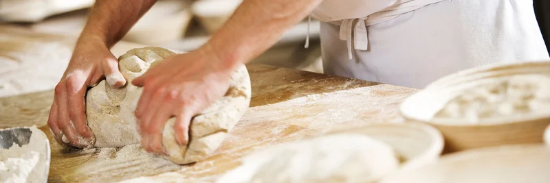 Teig kneten: Ausbildung im Bio-Lebensmittelhandwerk Teig wird auf einer Arbeitsfläche geknetet.