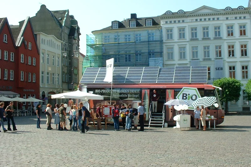 Bus steht in der Innenstadt von Schwerin, davor Menschen und Zelte.