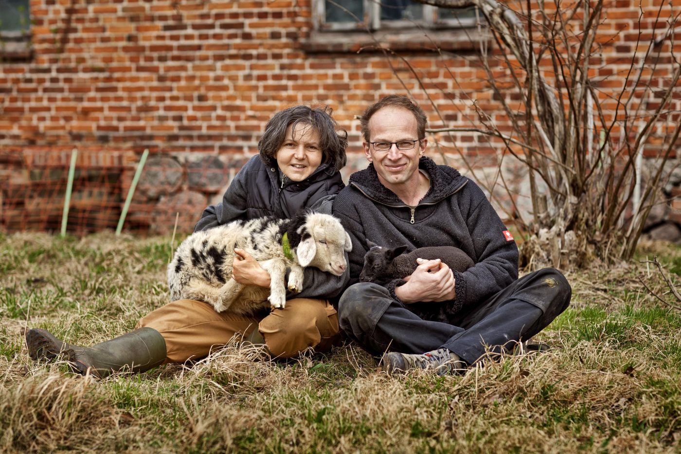 Mann und Frau mit Schafen im Arm